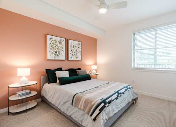 A bedroom with a bed, nightstands, and a window.