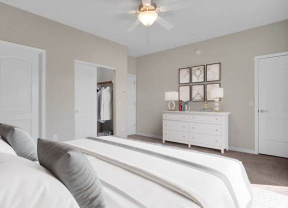 A white bedroom with a bed, dresser, and mirror.