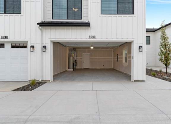 A white garage door is open to reveal a spacious garage.