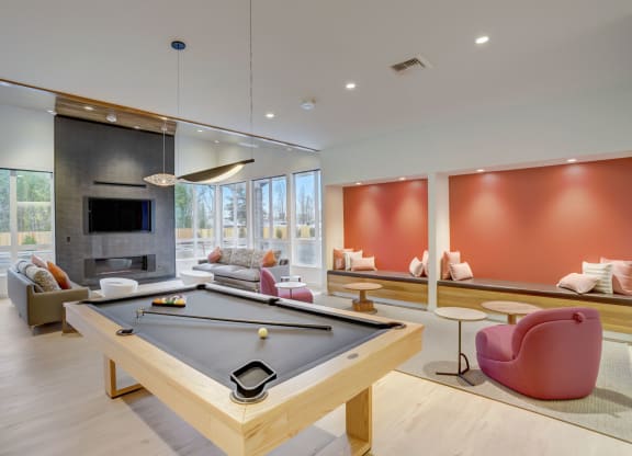 a pool table in the center of a living room with couches and a fireplace
