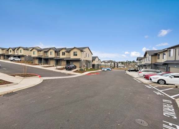 A street view of a residential area with houses and parked cars.