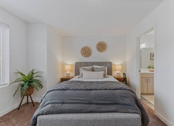 A bedroom with a large bed and a potted plant.