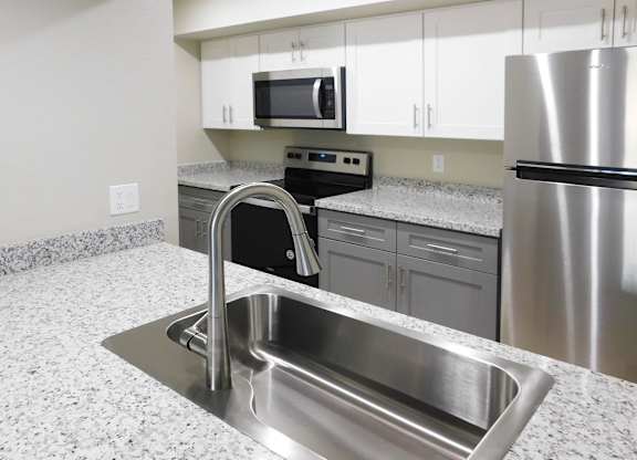 A kitchen with a stainless steel sink and refrigerator.