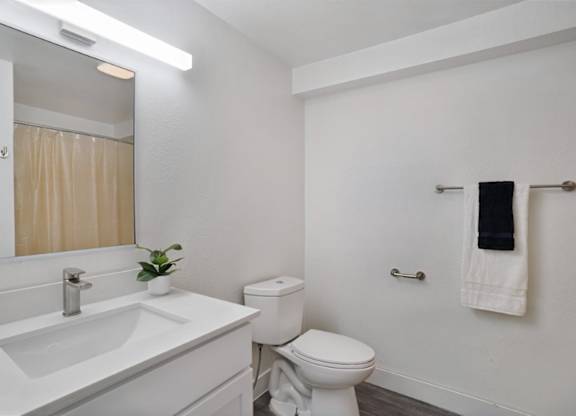 A white bathroom with a toilet, sink, and mirror.
