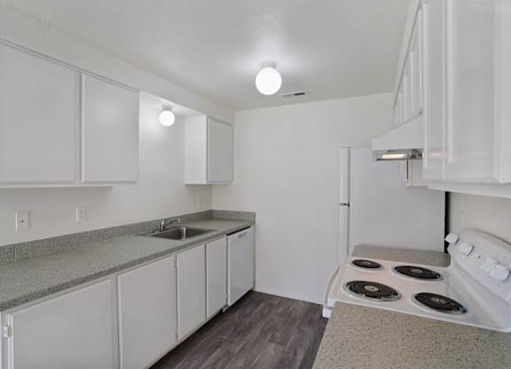 A kitchen with white cabinets and a stove top oven.