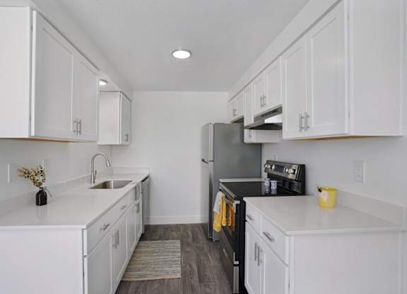 A kitchen with white cabinets and a black refrigerator.