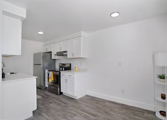 A kitchen with white cabinets and a grey refrigerator.