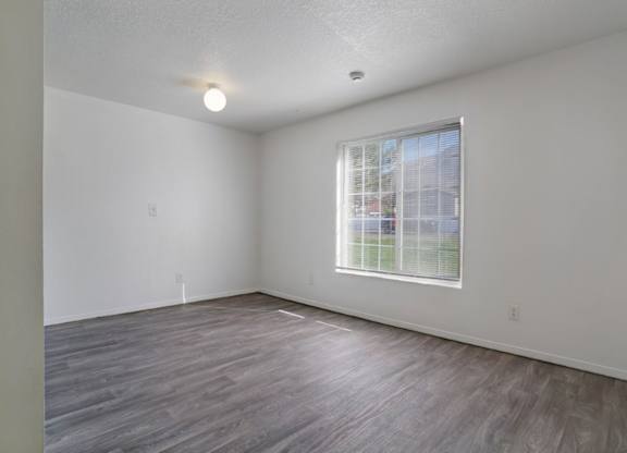 A room with a window and wooden flooring.