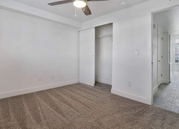 A room with a carpeted floor and a ceiling fan.