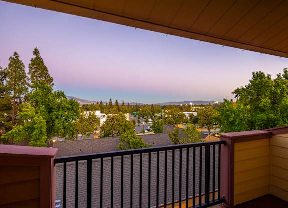 A balcony with a black railing overlooks a residential neighborhood.