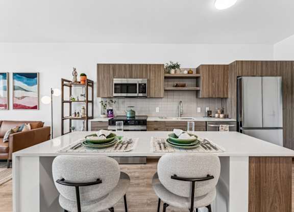 A modern kitchen with a white island and two chairs.
