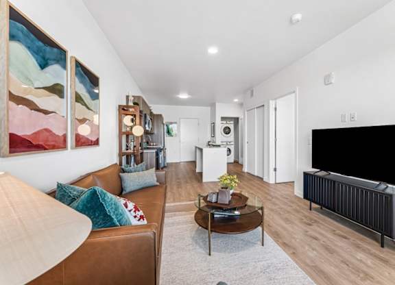 A living room with a brown couch and a painting on the wall.