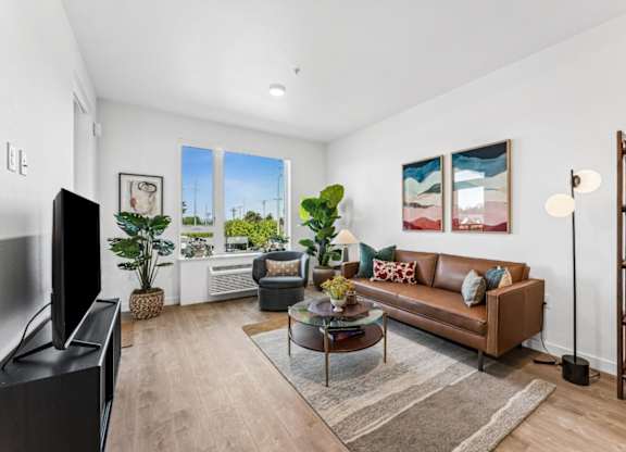 A living room with a brown couch, a coffee table, and a flat screen TV.
