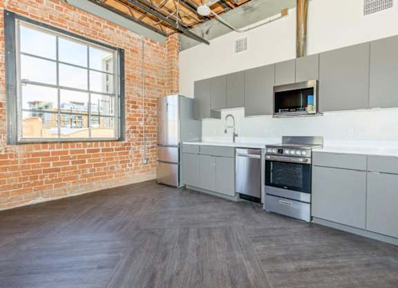 A kitchen with a brick wall and stainless steel appliances.