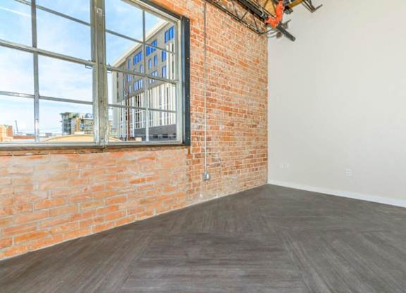 A room with a large window and a brick wall.