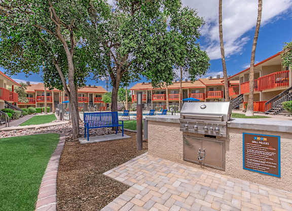 A BBQ grill is in the middle of a landscaped courtyard.