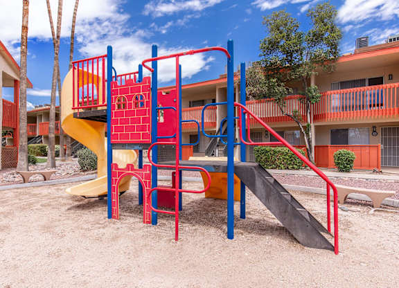A playground with a red and yellow slide and a red and blue climbing frame.