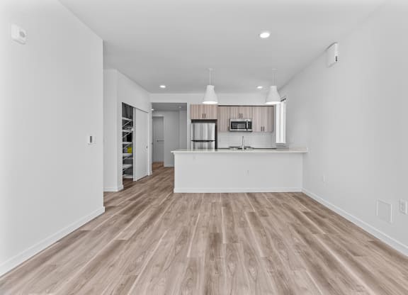 the living room and kitchen in a new home with white walls and wood flooring