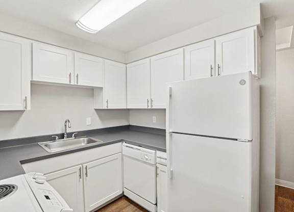 A white refrigerator is in a kitchen with white cabinets.