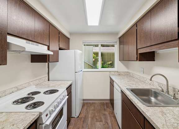 A kitchen with white appliances and brown cabinets.