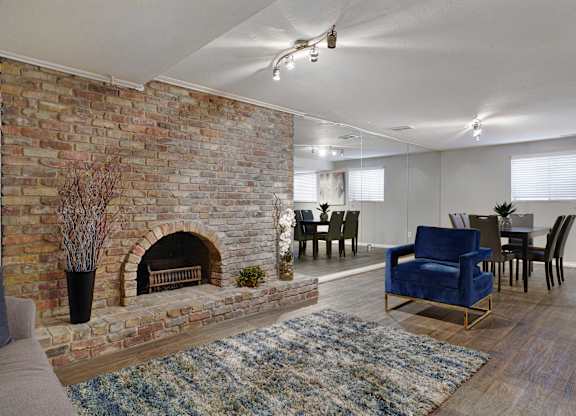 A living room with a brick fireplace and blue chairs.