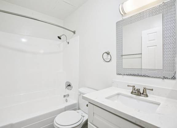 A white bathroom with a toilet, sink, and shower.