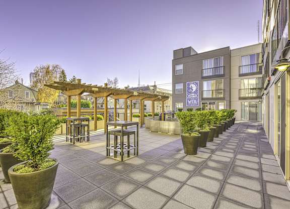 A patio area with a wooden pergola and potted plants.