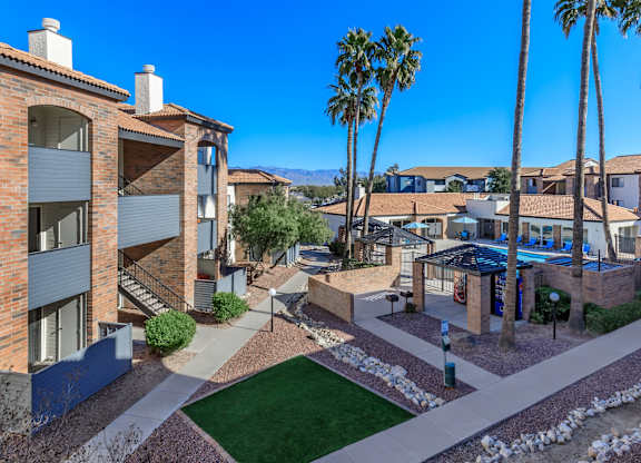 A sunny day at a residential complex with a pool and palm trees.
