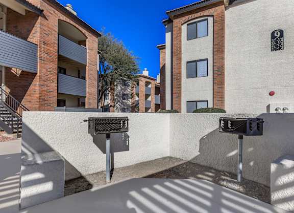 A parking meter is in front of a building with a tree in the background.