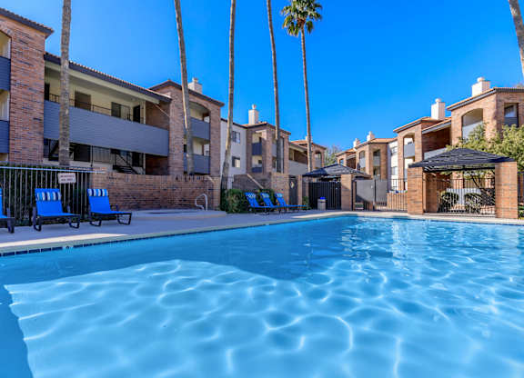 A swimming pool surrounded by palm trees and apartment buildings.