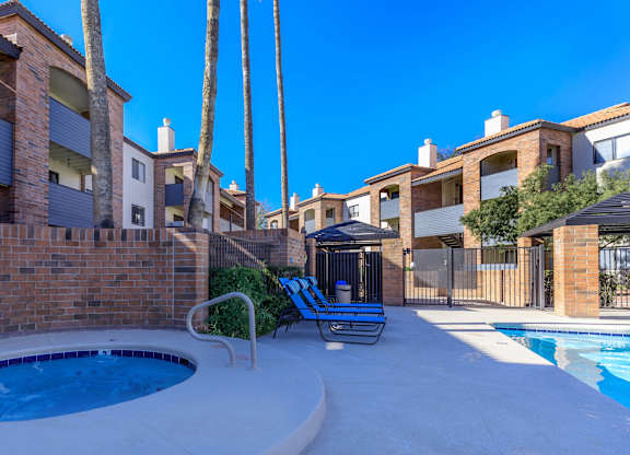 A pool surrounded by a brick wall and palm trees.