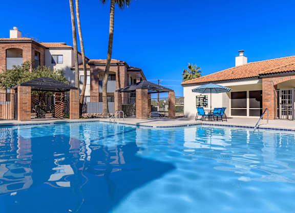 A swimming pool in front of a house with a blue sky.
