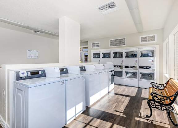 A laundry room with a row of washers and dryers.