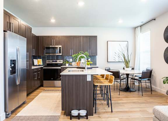 A modern kitchen with a refrigerator, sink, and dining table.