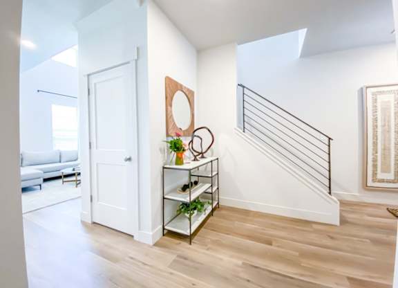 A white door is on the left side of a hallway with a wooden floor.