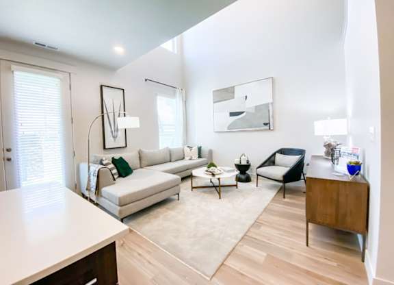 A modern living room with a white couch, a black chair, and a wooden cabinet.