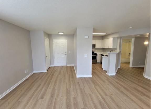 an empty living room and kitchen with wood flooring