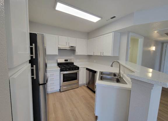 a kitchen with white cabinets and stainless steel appliances