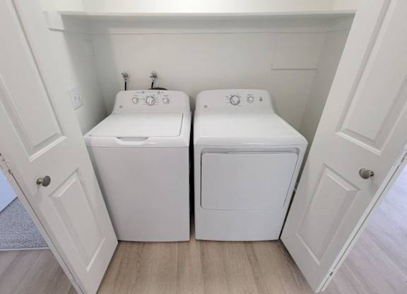 a washer and dryer in a laundry room with white cabinets