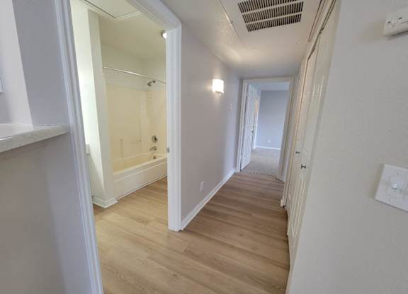 a renovated hallway with wood flooring and white walls