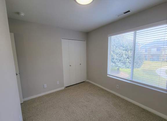 a bedroom with a large window and a closet