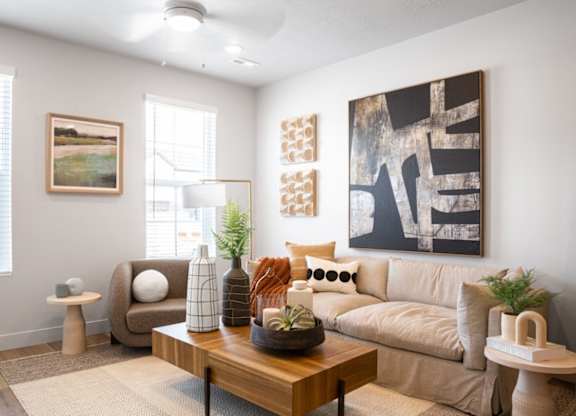 A living room with a brown couch, a wooden coffee table, and a large abstract painting on the wall.