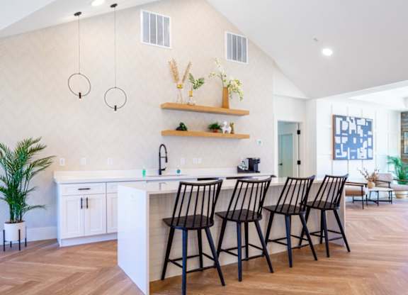 A kitchen with a white counter and black chairs.