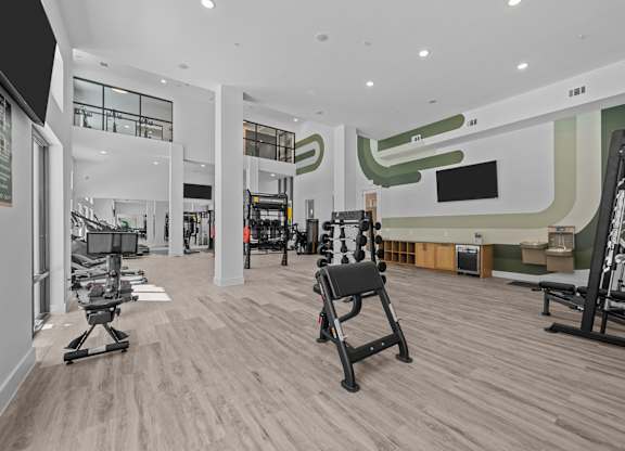 A gym with a variety of equipment including treadmills, weights, and exercise machines.