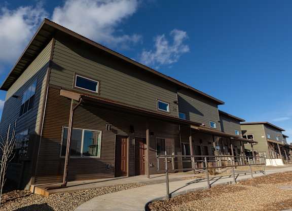 A modern house with a brown and grey exterior and a clear blue sky in the background.