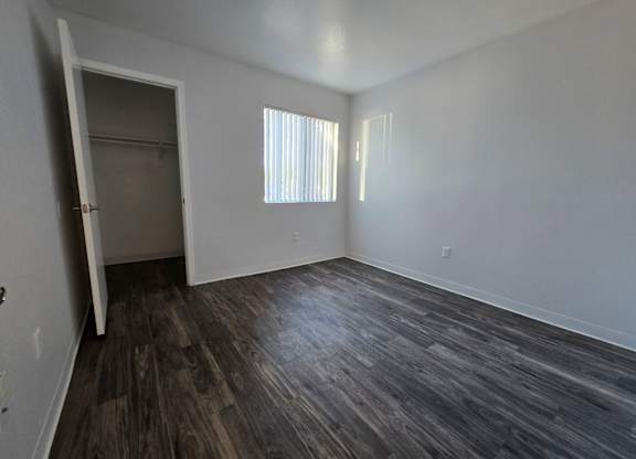A room with a wooden floor and a window with blinds.