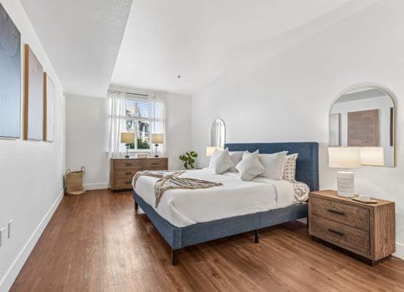 A bedroom with a bed, nightstand, and a window with curtains.
