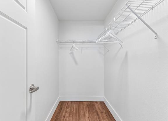 A white closet with a door and a shelf.