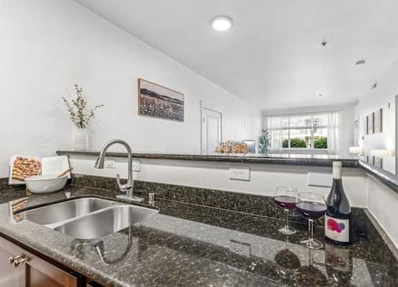 A kitchen with a granite countertop and a stainless steel sink.