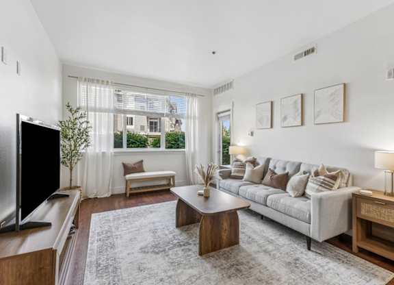 A living room with a grey couch, a wooden table, and a television.